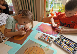 Dziewczynka ryauje dynię na brązowym kartonie