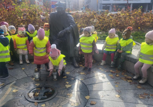 Dzieci kładą znicze pod pomnikiem