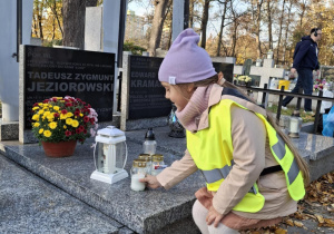 Dziewczynka stawia znicz na grobie