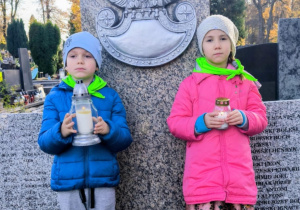 Dzieci stojące przed pomniekiem AK ze zniczami