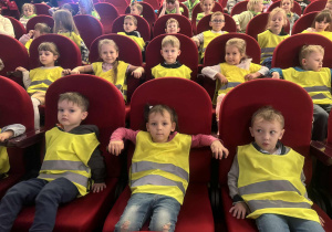 Dzieci siedzą w teatrze na krzesłach