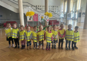 Dzieci z grupy drugiej w holu teatralnym przy żółtych kwiatach