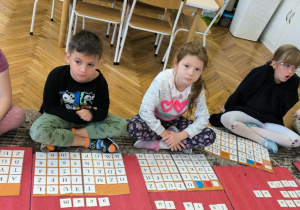 Dzieci siedzą przed ruchomym alfabetem