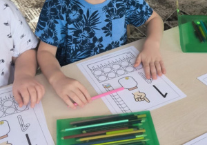 Chłopiec wypelnia kartę pracy z cyfrą jeden