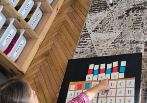 Dziewczynka z ułożonym wyrazem z liter ruchomego alfabetu