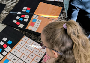 Dziewczynka siedzi przed wielkimi literami ruchomego alfabetu