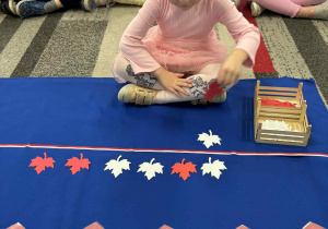 Dziewczynka przyklada czerwony liść