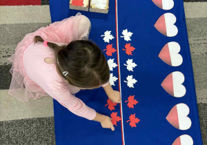 Dziewczynka układa liście biało-czerwone