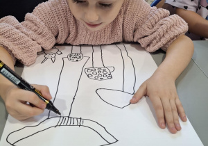 Dziewczynka czarnym mazakiem rysuje muchomory