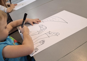 Chłopiec przy stoliku rysuje muchomory