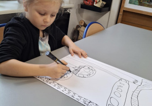 Chlopiec czarnym mazakiem rysuje ilbrzymie muchomory