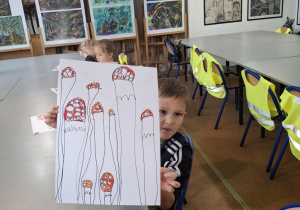 Chłopiec pokazuje pomalowane na czerwono muchomory