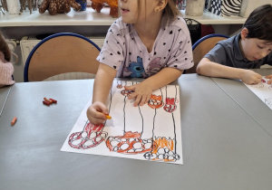 Dziewczynka koloruje kapelusze muchomorów na czerwono