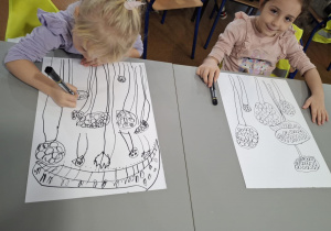 Dziewczynki przy stole rysują muchomory