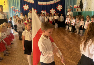 Chłopiec idzie z biało czerowną flagą