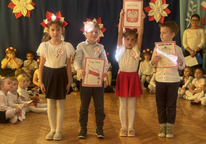 Dziewczynka podnosi planszę z Godłem Polski