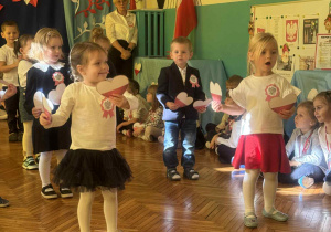 Dzieci z biało czerownymi sercami śpiewają pisoenkę