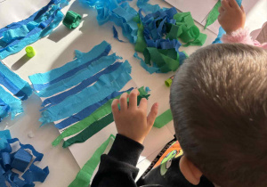 Chłopiec przykleja zieloną bibułę