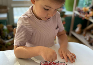 Dziewczynka stawia czrwone kropki