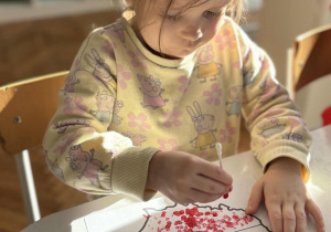 Dziewczynka patyczkiem do uszu robi czerwone kropki