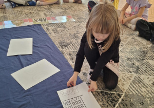 Dziewczynka przykłada puzzel z domkiem