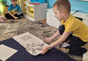 Chlopiec przykłada puzzel z orłem