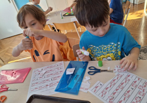 Chłopcy przy stole wycinają małe flagi