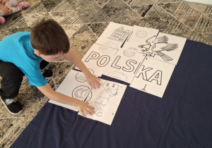 Chłopiec przyklada puzzel z chłopcem z flagą