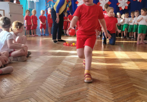 Dziewczynka biegnie z czerwoną piłką