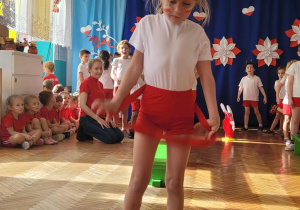 Dziewczynka przechodzi przez czerwoną szarfę