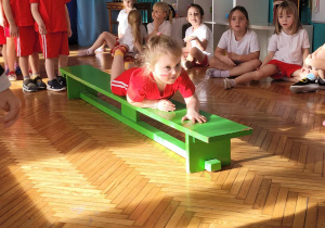 Dziewczynka prześlizguje się po ławeczce