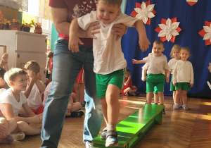 Chłopiec z asekurajcą zeskakuje z ławeczki