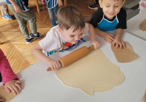 Chłopiec z całej siły rozwałkowuje ciasto