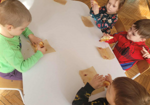 Dzieci przy stole jedzą rogale