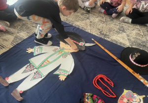 Chlopiec przykłada do sylwety górala czapkę