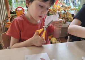 Chlopiec wycina nożyczkami