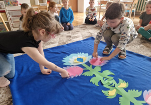 Dzieci dokladają dwa czerwone płatki do wzoru łowickiego