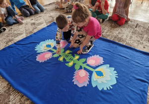 Dzieci układają zielone elementy do wzoru łowickiego