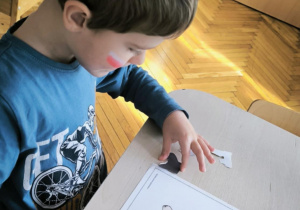 Chłopiec przykleja elementy stroju łowickiego