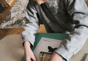 Dziewczynka przykleja elementy stroju łowickiego