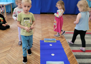 Dzieci maszerują wokół niebieskiej bibuły