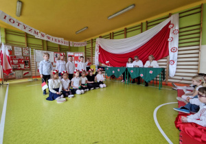 Dzieci siedzą z instrumentami i flagami