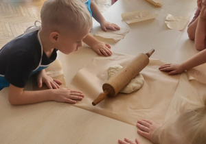 Chłopiec przygląda się ciastu na którym lezy wałek