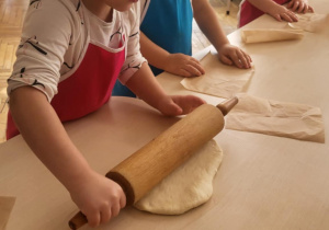 Dziewczynka na papierze do pieczenia wałkuje ciasto