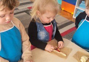 Dzieci rozsmarowują dżem po cieście