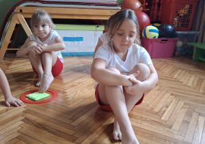 Dziewczynka wklada zielony woreczek do zielonego koła