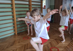 Dziewczynka staje jak żuraw na jednej nodze z woreczkiem