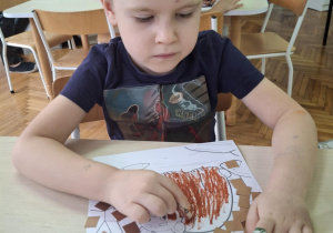 Chłopiec brązowym papierem wykleja gawrę niedźwiedzia