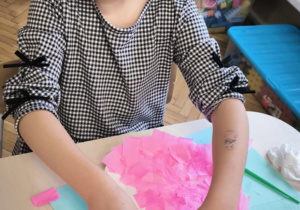 Dziewczynka wykleja talerzyk różową bibułą