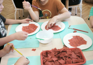 Chłopiec wykleja brązową bibułą talerzyk